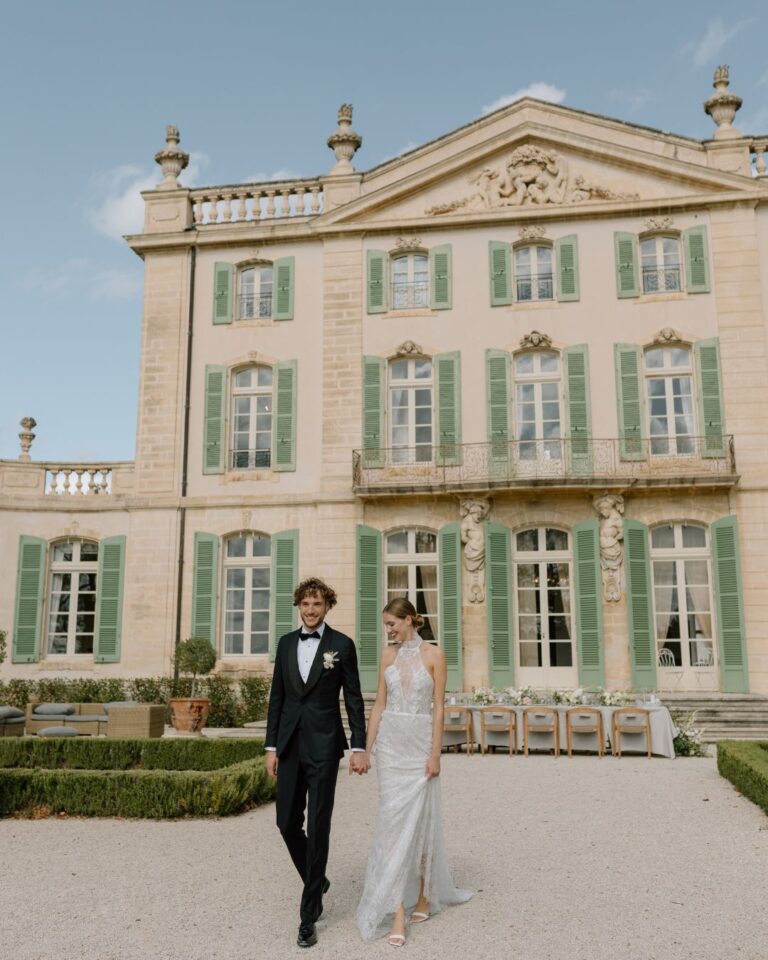 Bride and groom walking hand-in-hand in front of the stunning venue, with a romantic atmosphere, captured by Arlene Leilani.