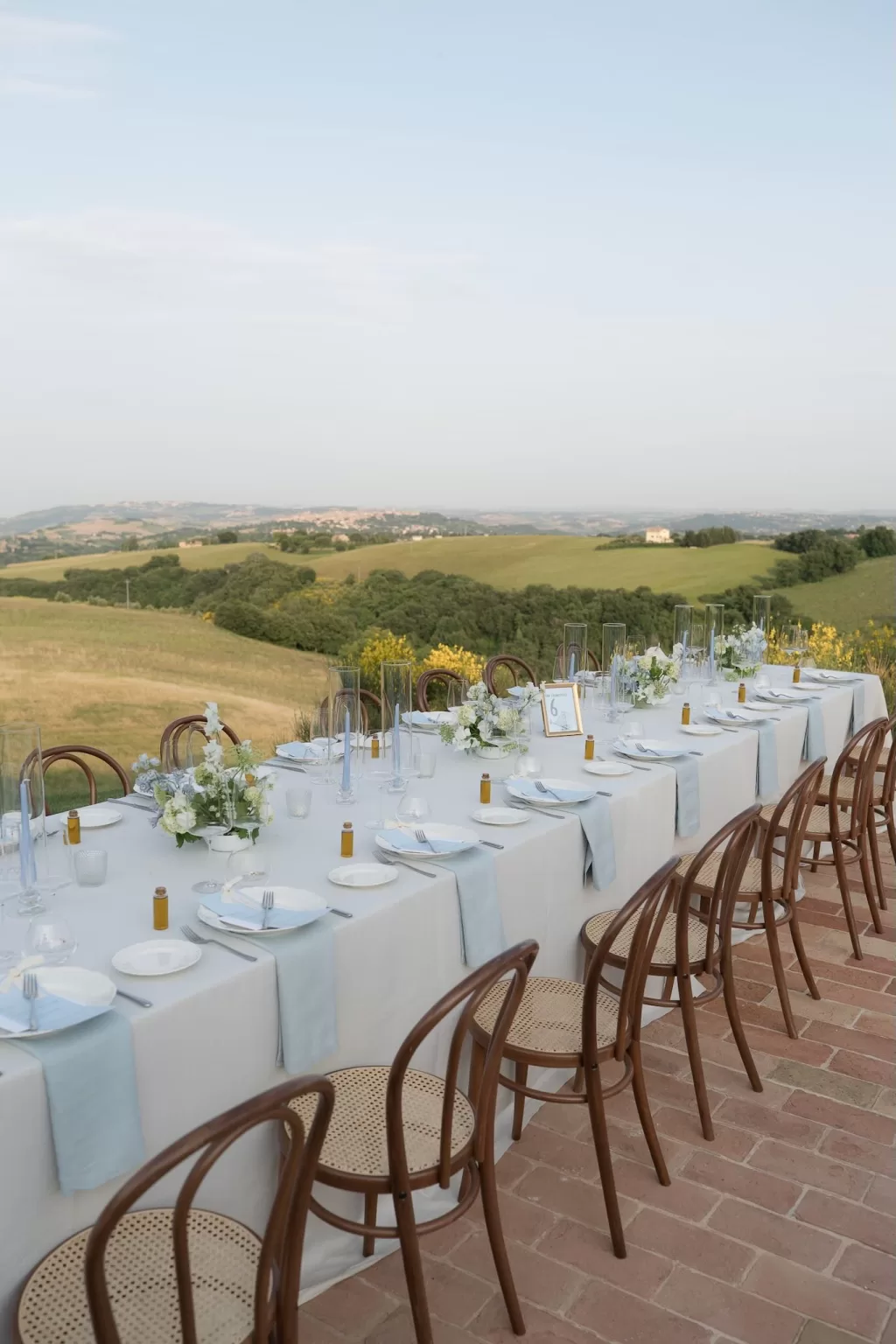 Elegant wedding table setup with blue napkins and countryside views at sunset at Casa Olivi.