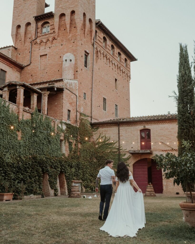 The bride and groom standing together against the breathtaking backdrop of Castello di San Fabiano's estate, photographed by Bella Weddings.