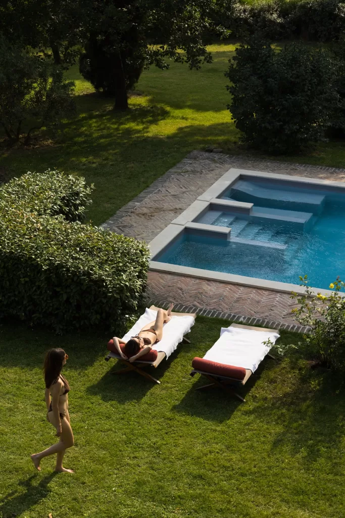 Swimming pool and sun loungers set against the historic brick façade of Castello di San Fabiano.