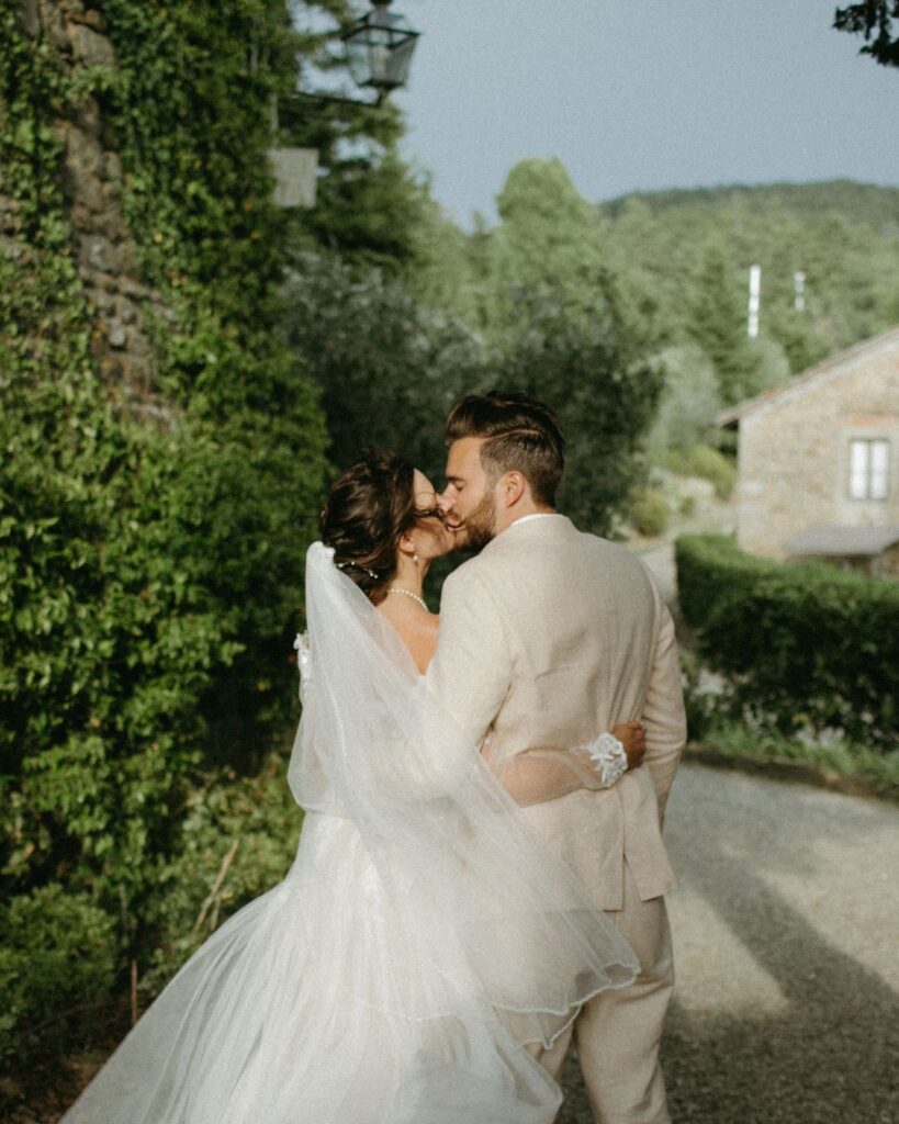 Newlyweds strolling hand in hand along the cobblestone paths of Castello di Ristonchi.
