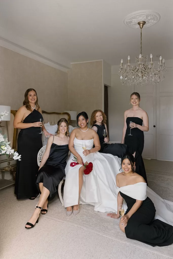 Bride and bridesmaids in chic black dresses celebrating together at Château de la Couronne.
