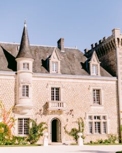 The grand exterior facade of Château de la Couronne, a fairytale wedding venue surrounded by lush greenery.