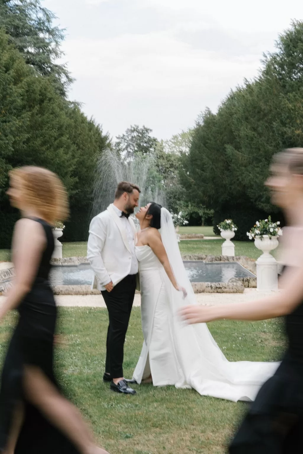 Bride and groom kissing by the fountain at Château de la Couronne gardens.