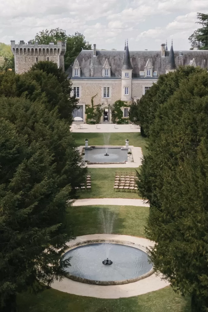 Aligned fountains leading to Château de la Couronne framed by trees.