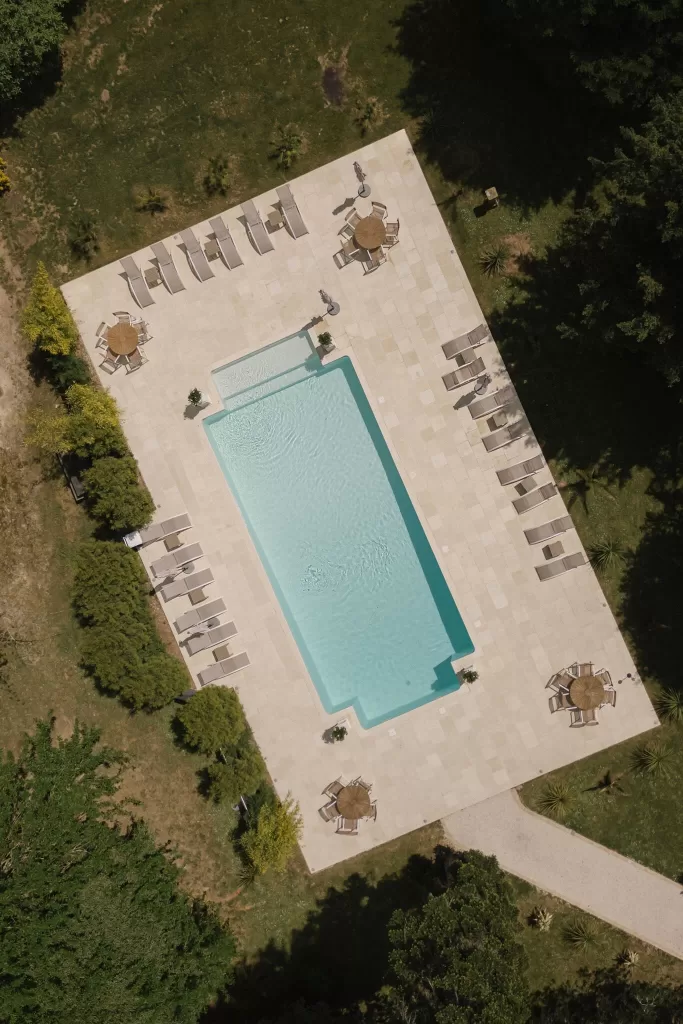 Aerial shot of the rectangular pool terrace with loungers and seating at Chateau de la Couronne.