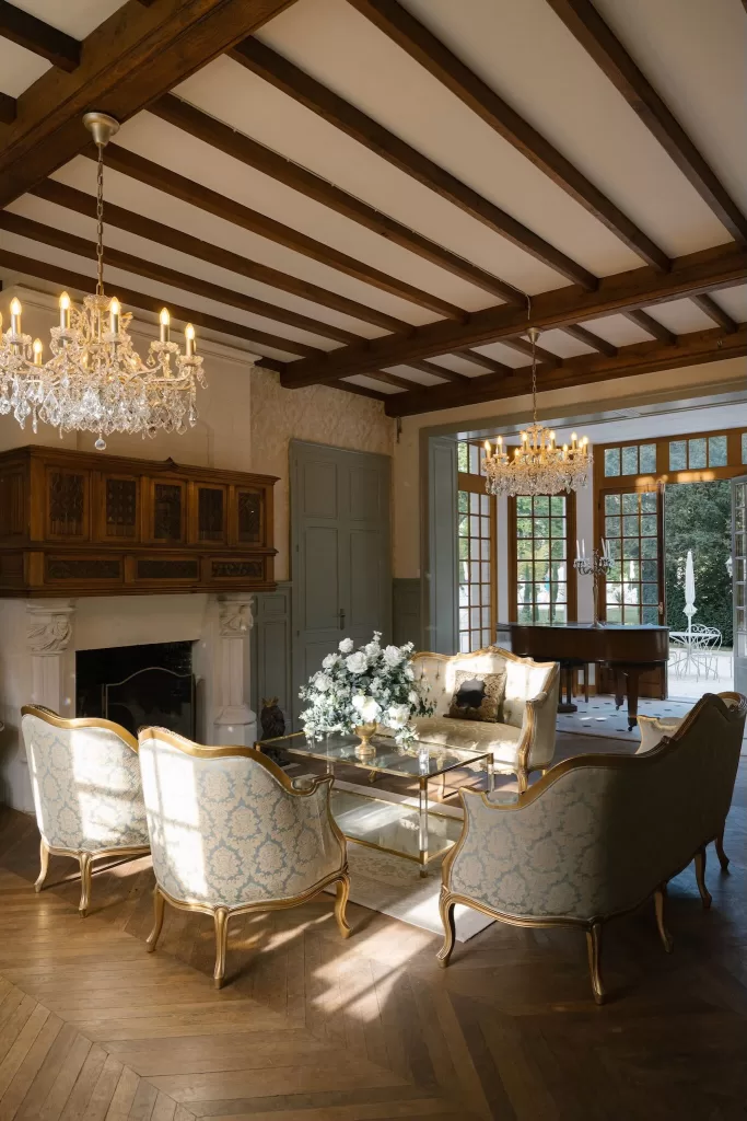 Elegant salon at Château de la Couronne with antique seating, chandeliers, and a glass coffee table decorated with flowers.