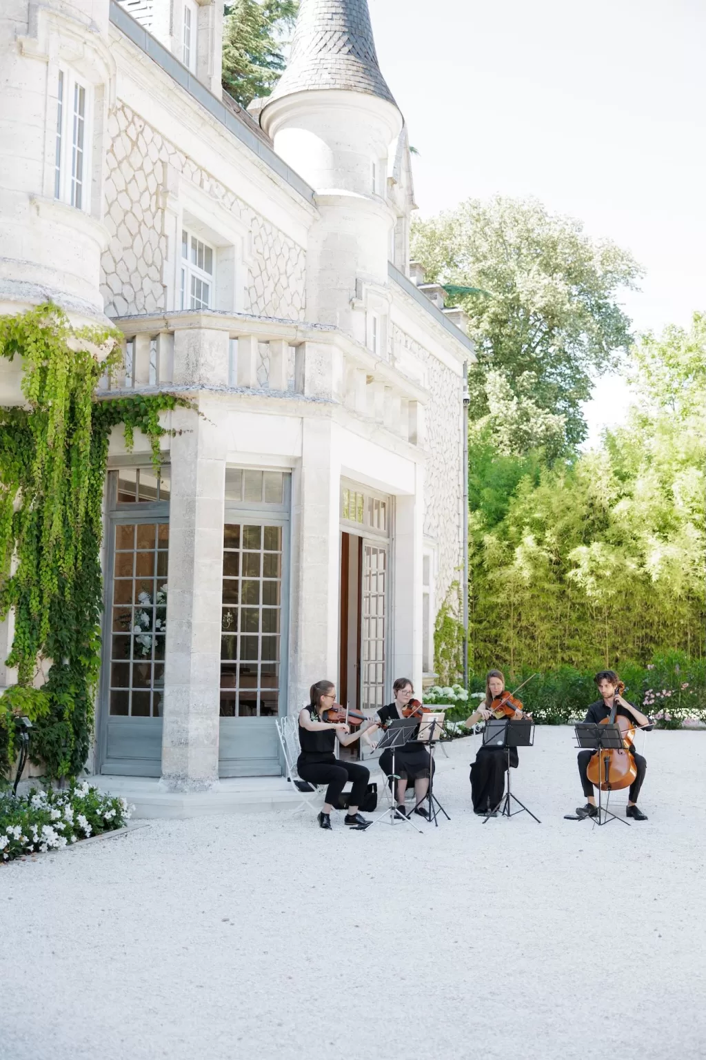 String quartet performing outdoors against the stone façade of Château de la Couronne.