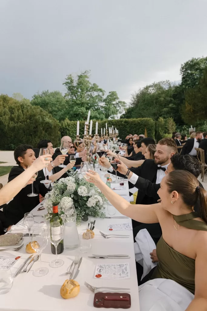 Guests raising glasses in a joyful wedding toast at Château de la Couronne’s outdoor reception.
