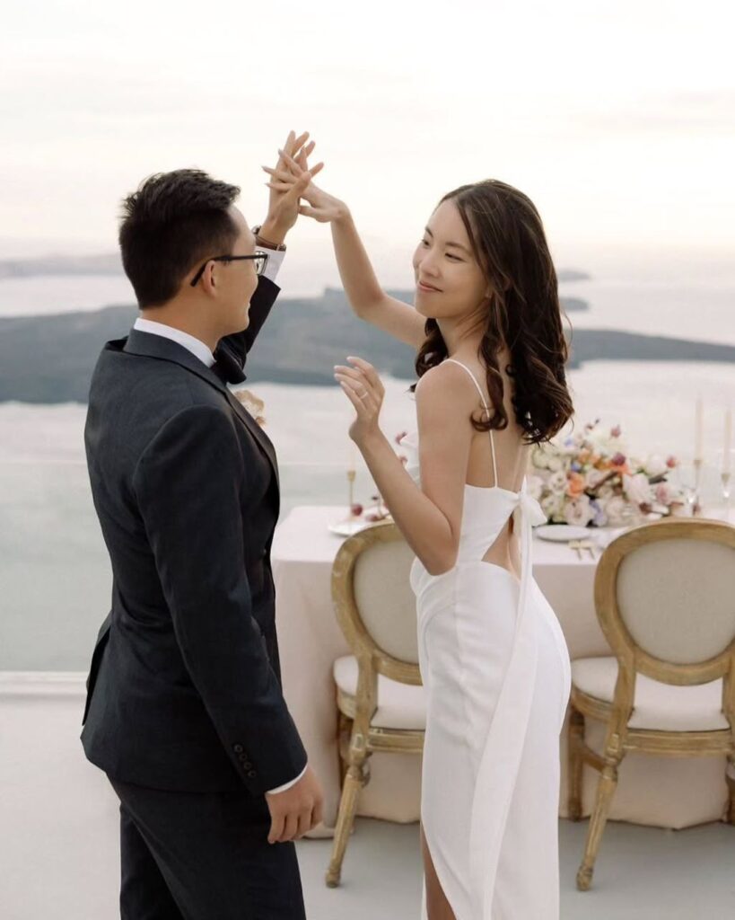 Newlyweds sharing an intimate moment at Cocoon Suites with a Santorini sunset backdrop