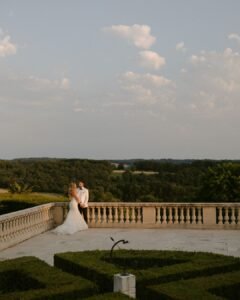 A romantic moment between the couple on the terrace of Domaine d'Essendieras, overlooking the rolling countryside at sunset.