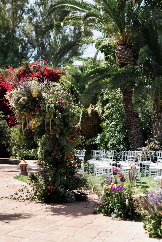 Floral ceremony arch surrounded by palm trees and garden paths at Finca La Concepción, set for an outdoor wedding.