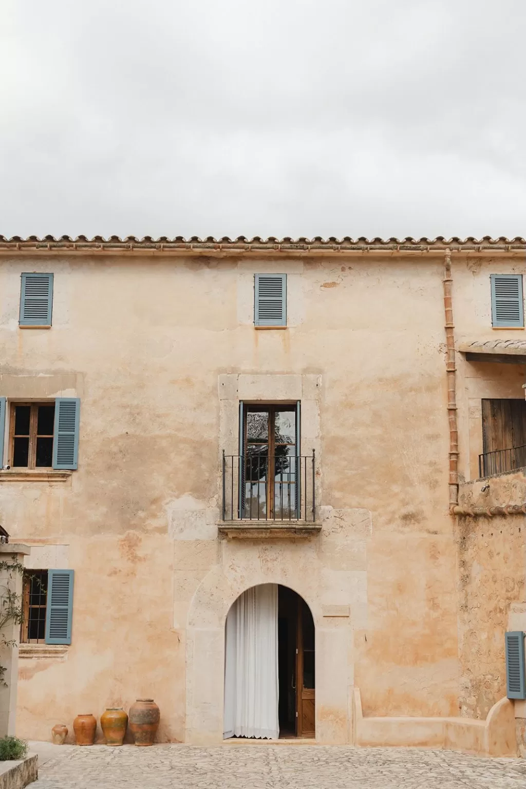 Bride and groom framed by the historic stone archway of Finca Son Sampol, bathed in soft afternoon light.