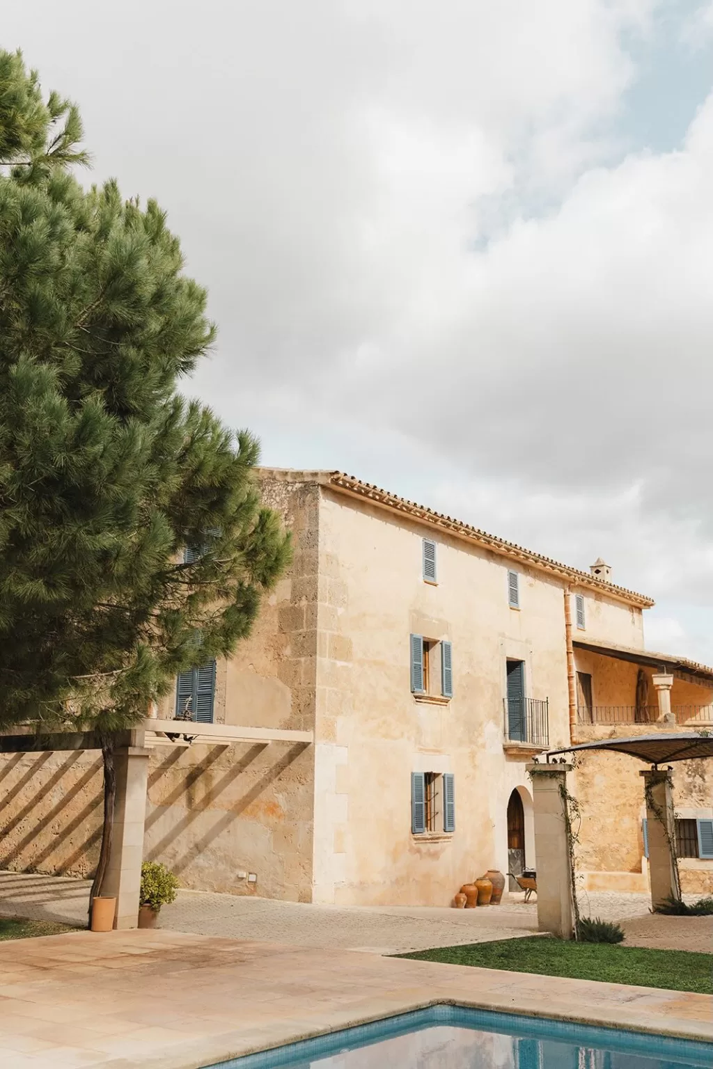 Traditional Mallorcan stone house with blue shutters and poolside terrace at Finca Son Sampol.