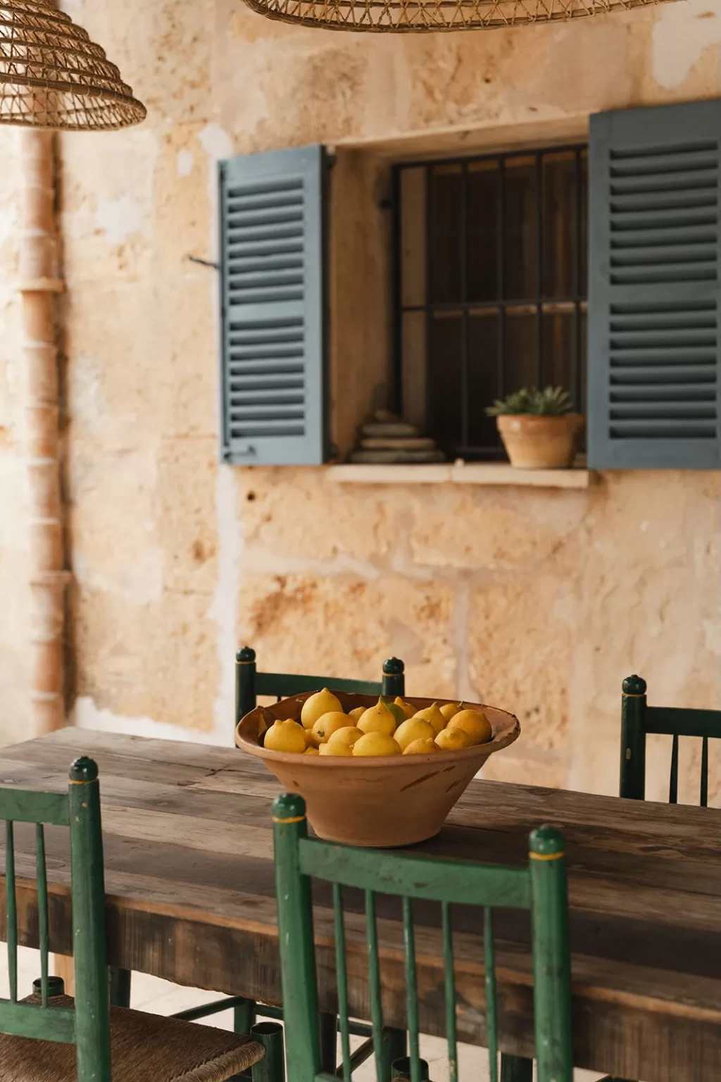 Bowl of fresh lemons on rustic wooden table under pergola at Finca Son Sampol.
