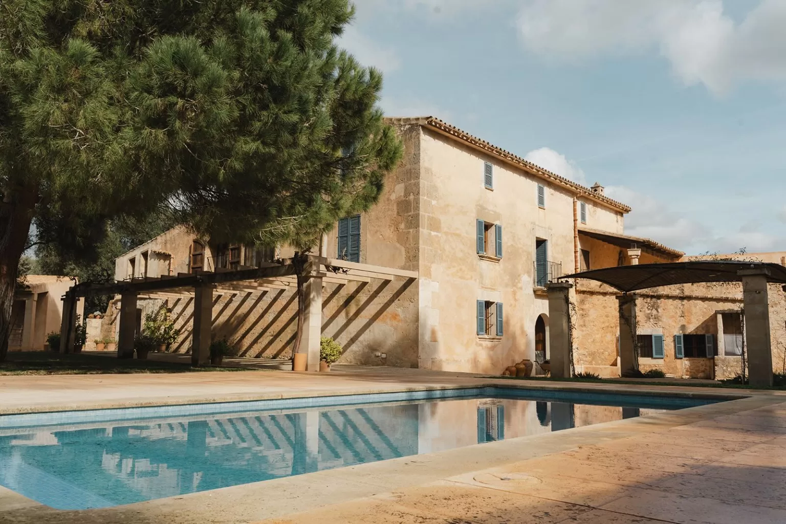Golden afternoon light on the pool and rustic stone house at Finca Son Sampol.