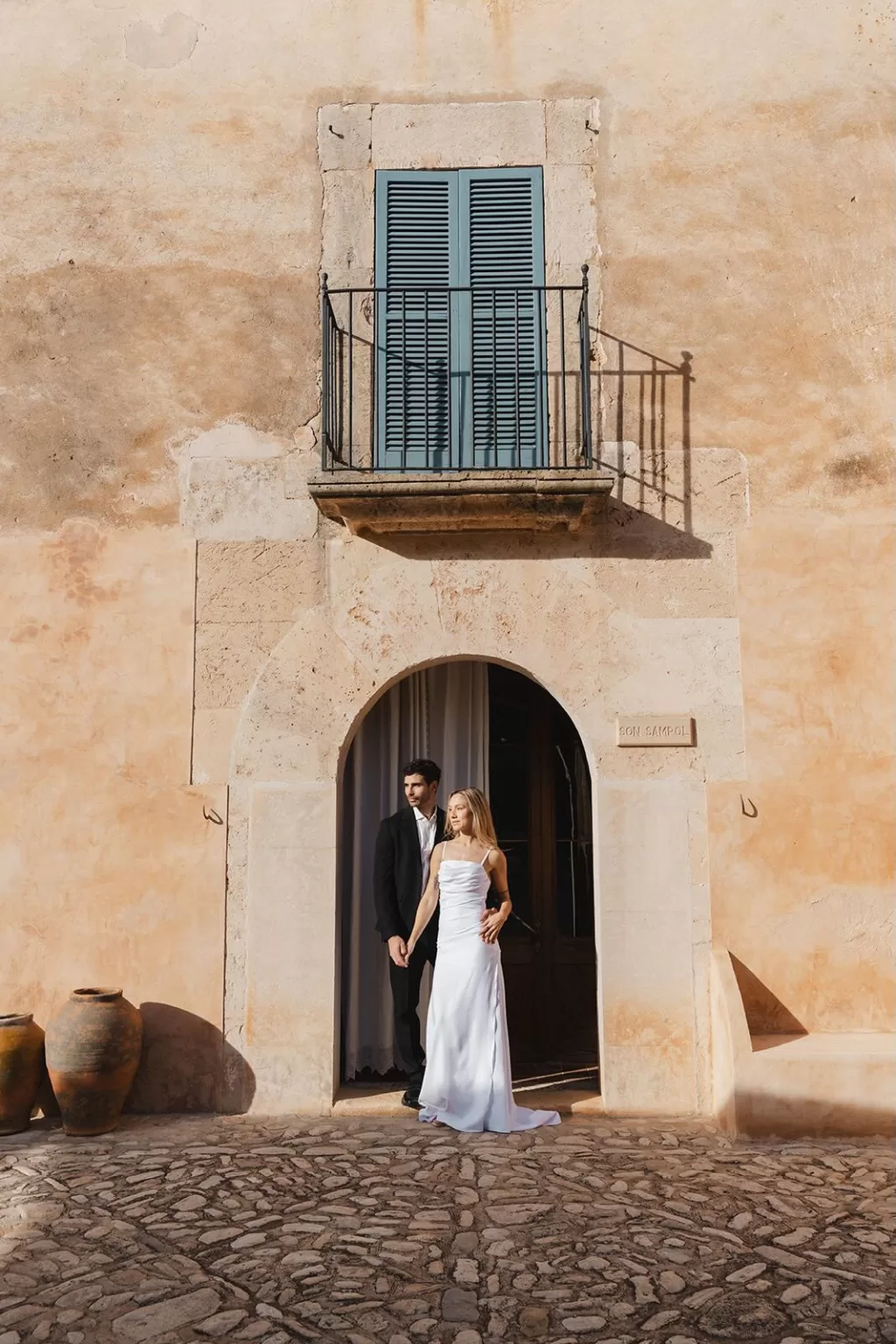 Wide view of the rustic stone facade with blue shutters at Finca Son Sampol, capturing Mediterranean charm.