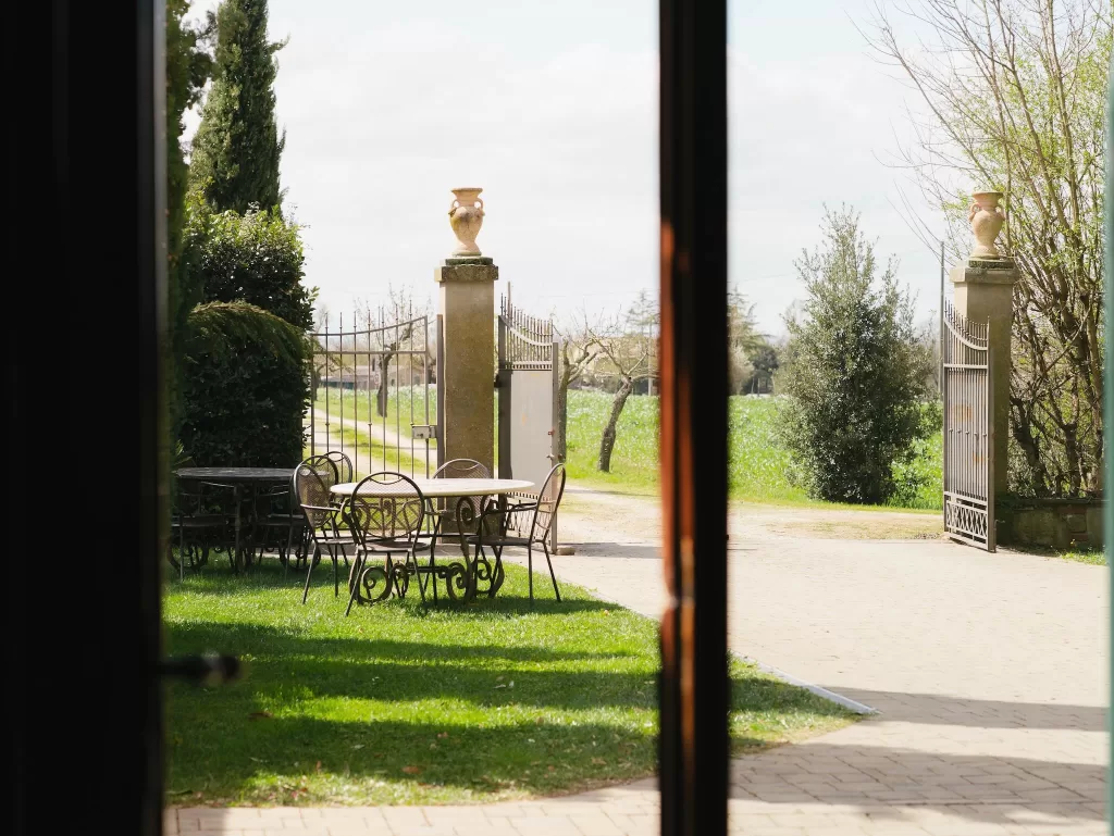 View from inside the villa looking out toward the wrought iron gate and garden seating at Villa Ivana Cortona.