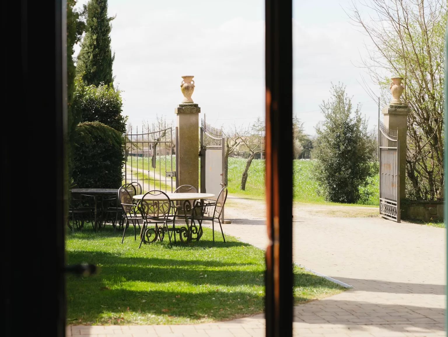 View from inside the villa looking out toward the wrought iron gate and garden seating at Villa Ivana Cortona.