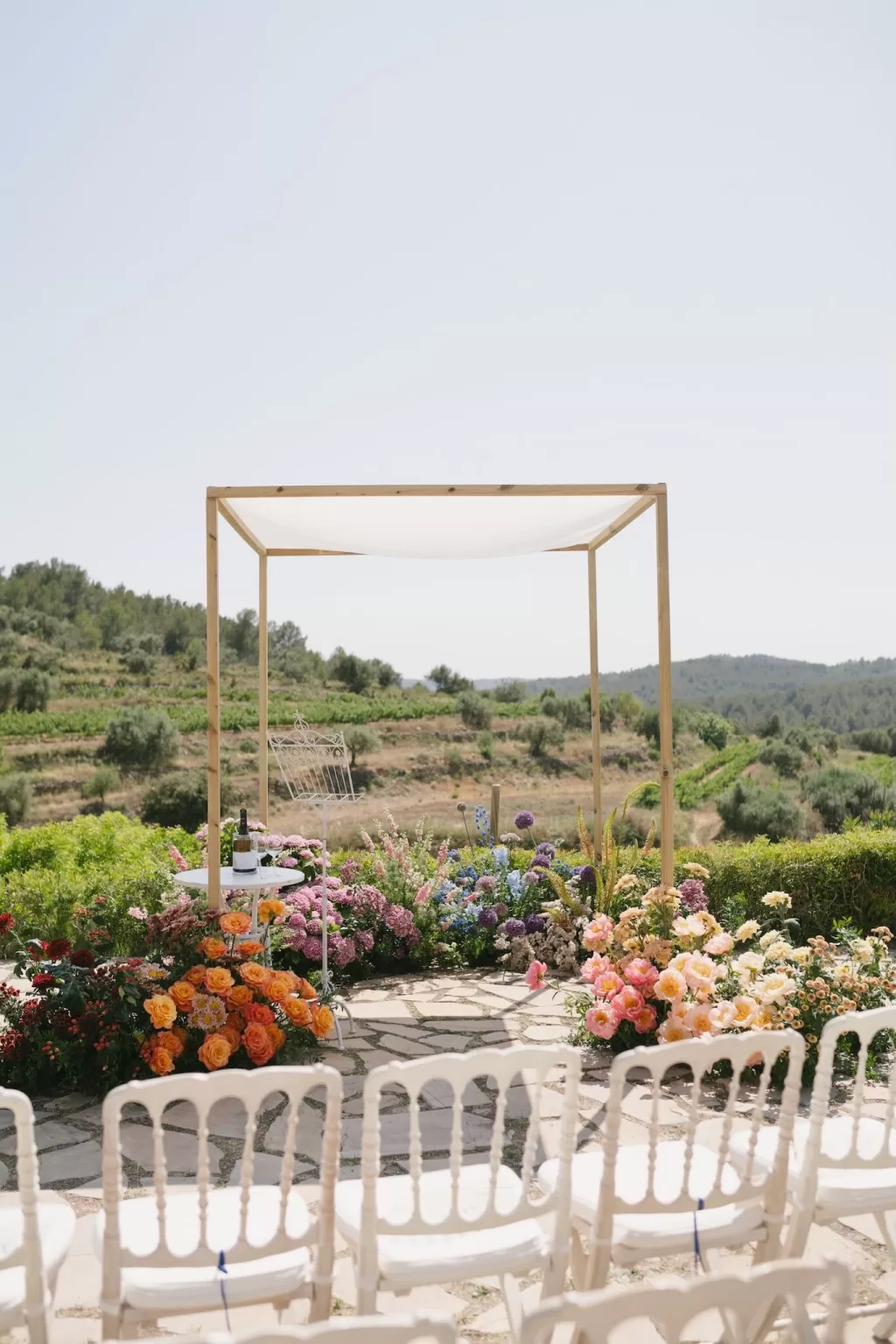 Colorful floral altar overlooking vineyard hills during ceremony setup at Masia Cabellut