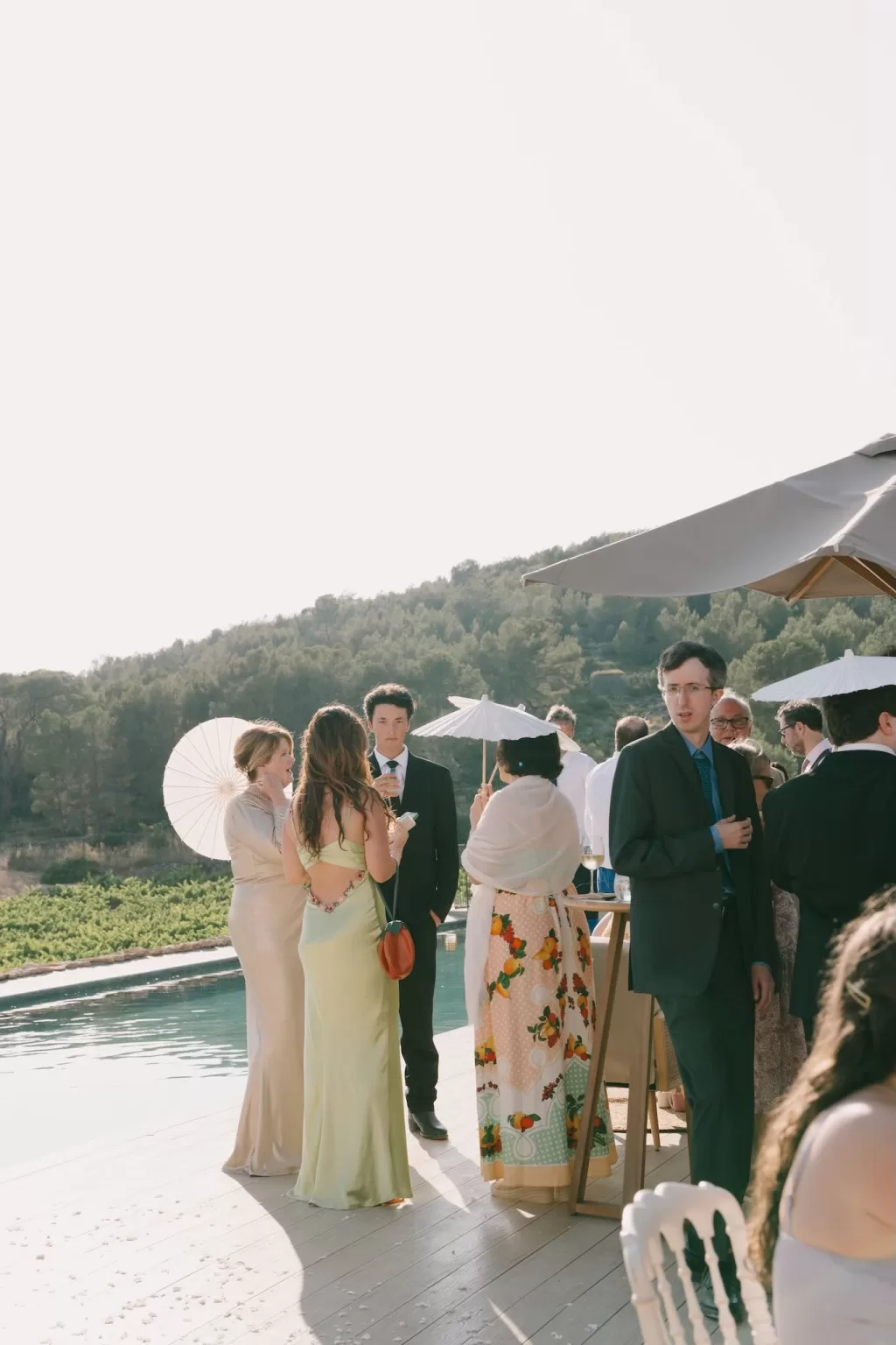 Guests mingling poolside with parasols during cocktail hour at Masia Cabellut