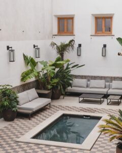 Inviting patio at Masia Cabellut with contemporary outdoor seating, lush tropical plants, and a stylish small pool for intimate gatherings.