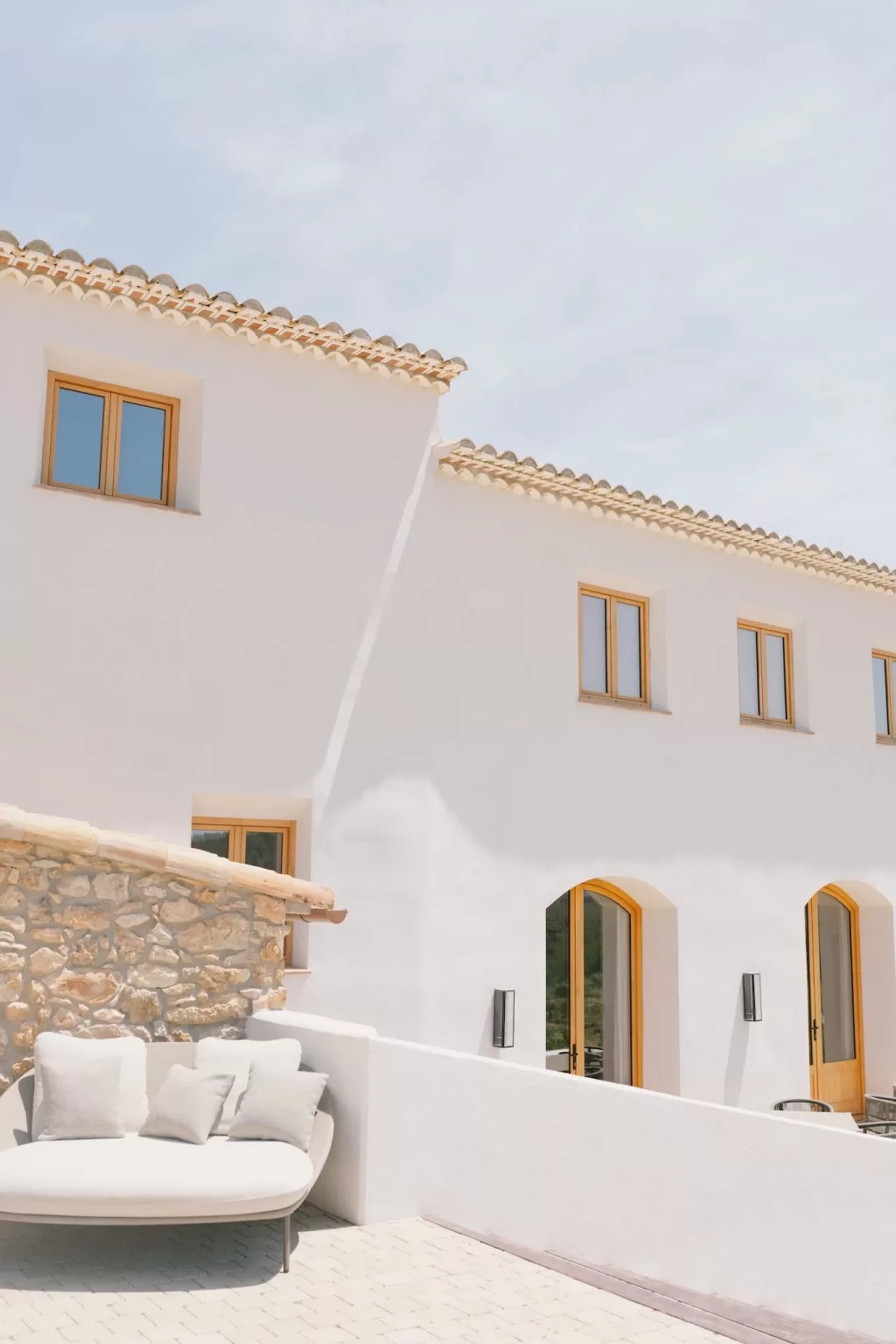 Whitewashed villa facade at Masia Cabellut with arched doors, golden window frames, and soft afternoon light