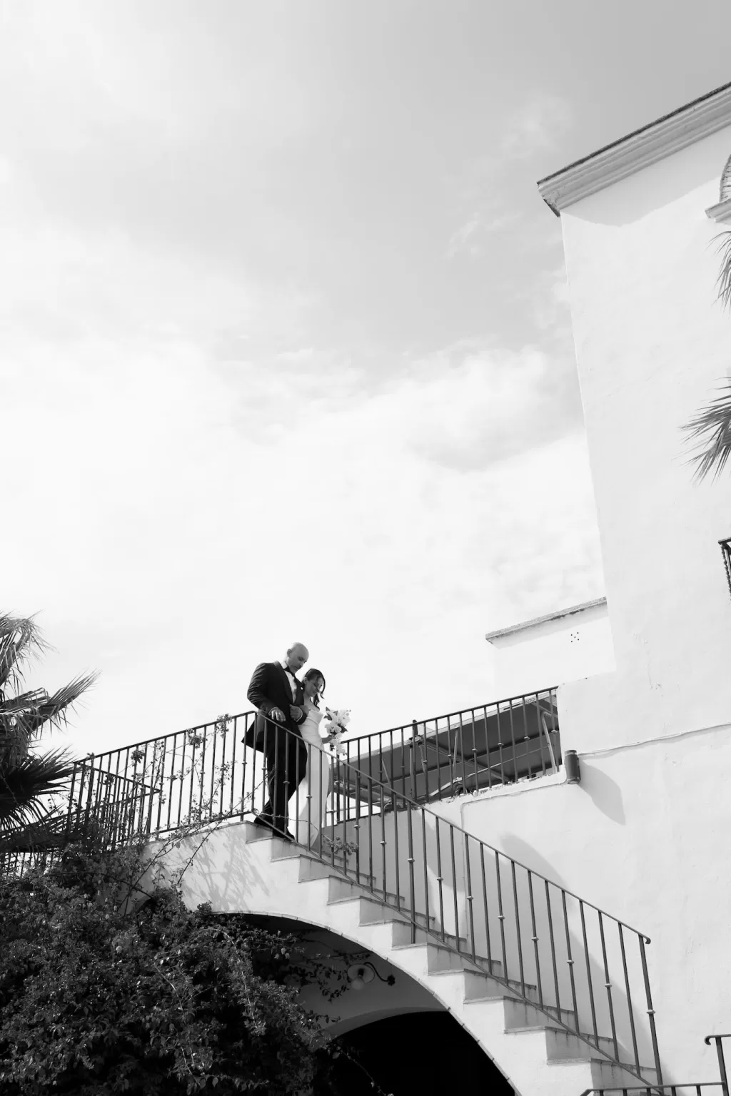 Black and white image of the bride walking down the staircase with her father at Masia Victoria.