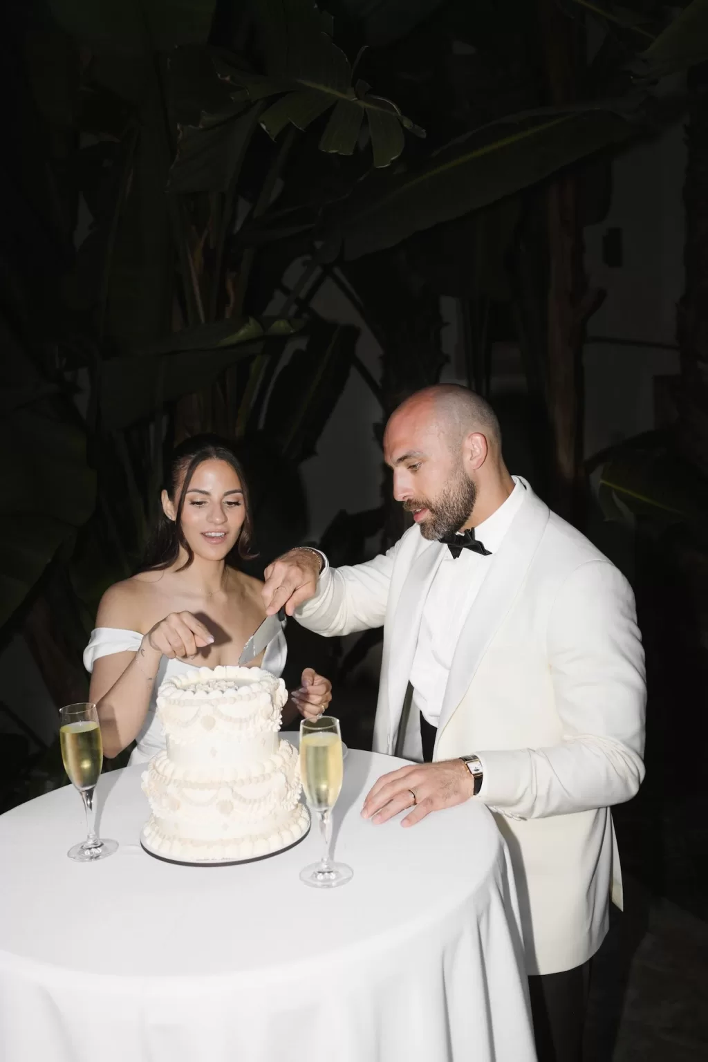 Bride and groom sharing a joyful moment while cutting their wedding cake at Masia Victoria.