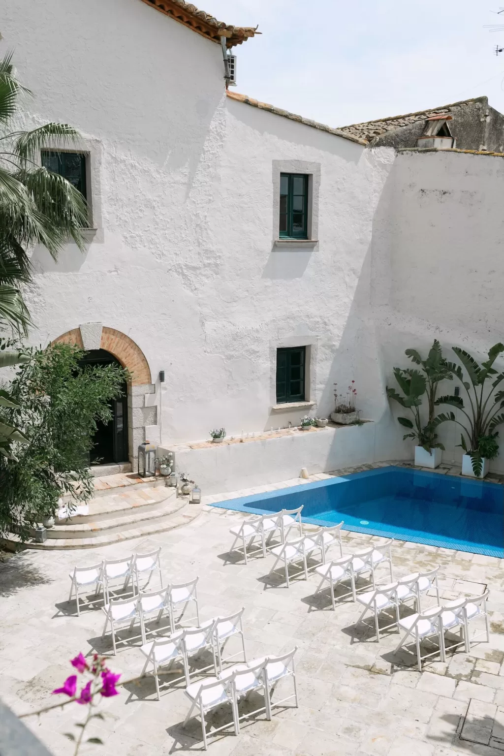 Outdoor poolside wedding ceremony setup with white chairs at Masia Victoria.
