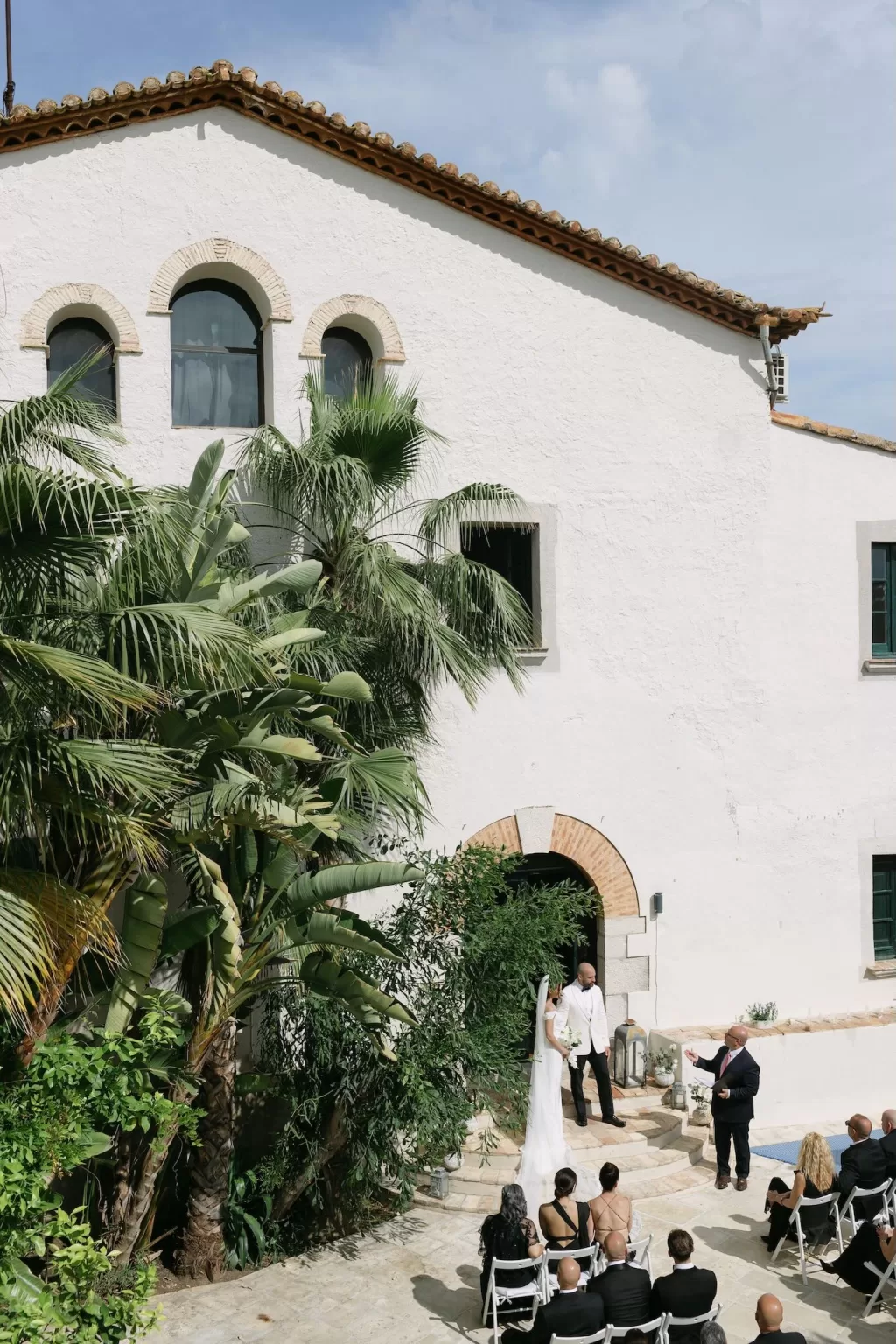 Wedding ceremony taking place in Masia Victoria’s courtyard surrounded by guests.