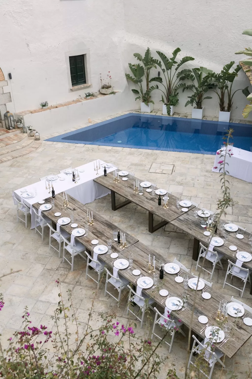 Rustic wooden tables arranged for a wedding reception beside the pool at Masia Victoria.