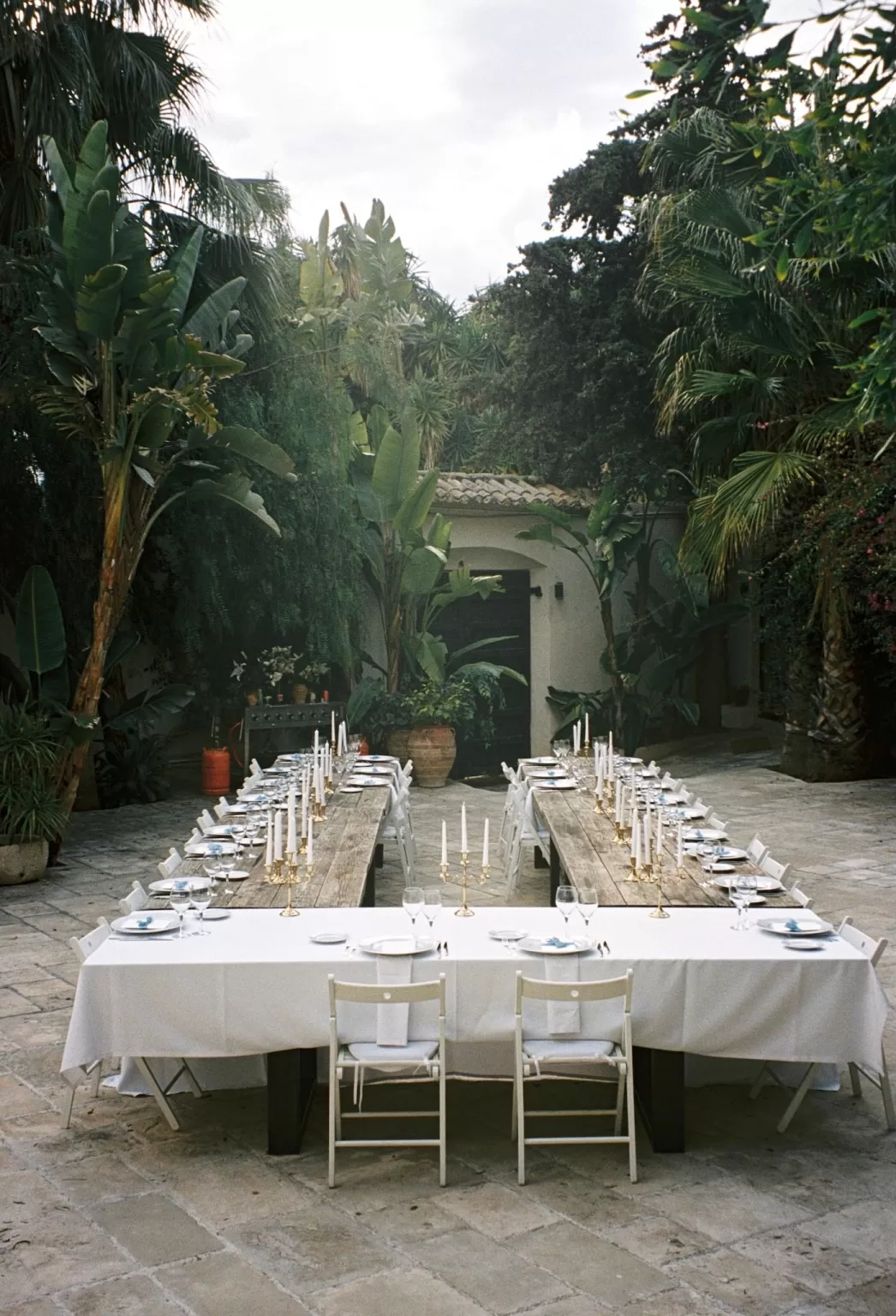 Long outdoor reception tables set with candles and white linens at Masia Victoria.