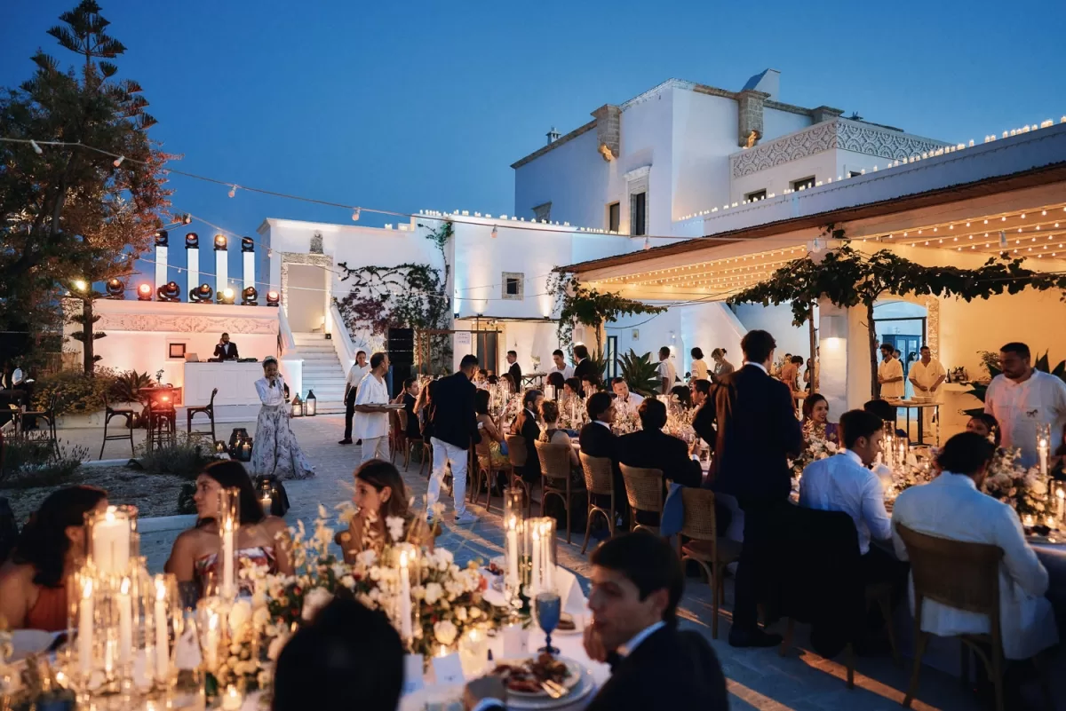 Guests dining under string lights during a summer wedding evening at Masseria Calderisi
