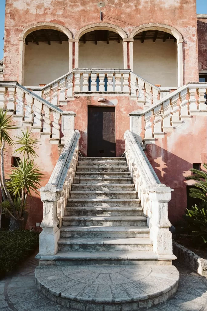 Sunlit stone staircase and arched balcony at Masseria Spina.