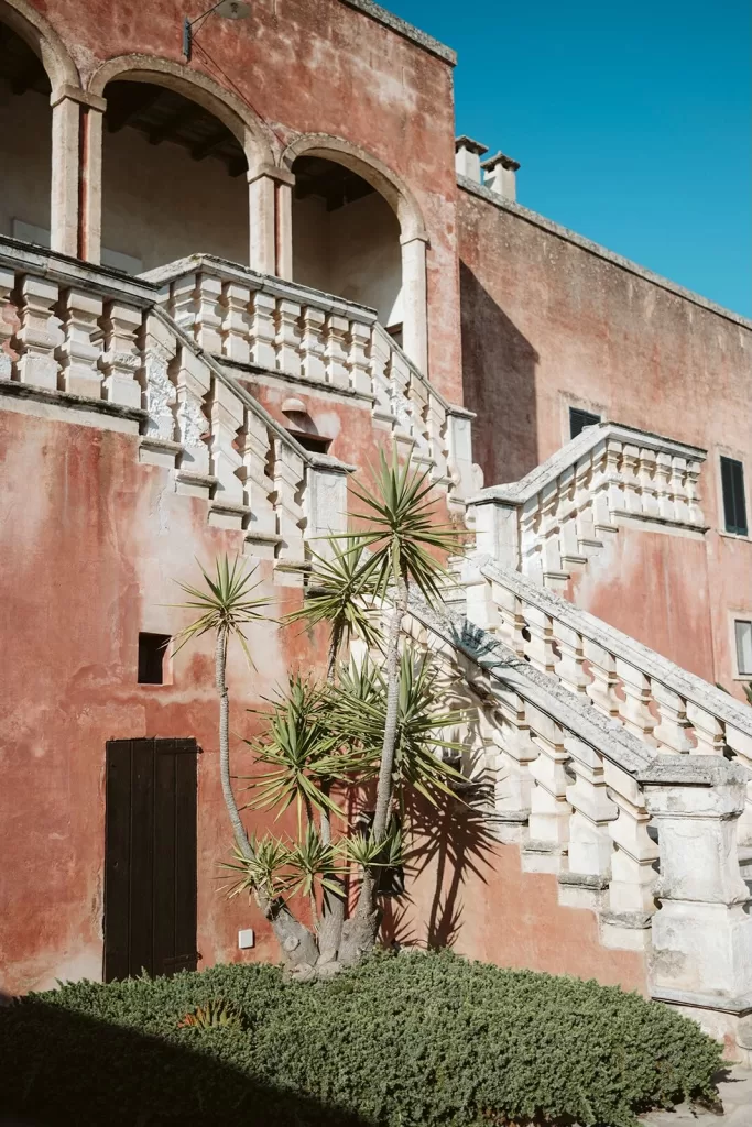 Sunlit view of the terracotta-toned staircase and Mediterranean plants at Masseria Spina, showcasing its timeless southern Italian charm
