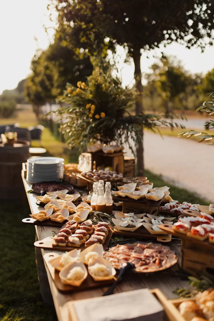 Abundant outdoor wedding aperitivo table with charcuterie, finger foods, and florals at Meneghetti Wine Hotel.