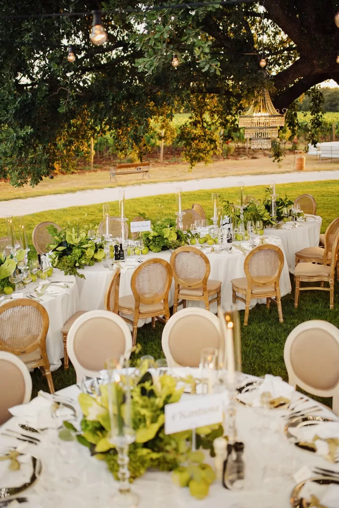 Close-up of beautifully decorated wedding tables with green centerpieces and apples at Meneghetti Wine Hotel