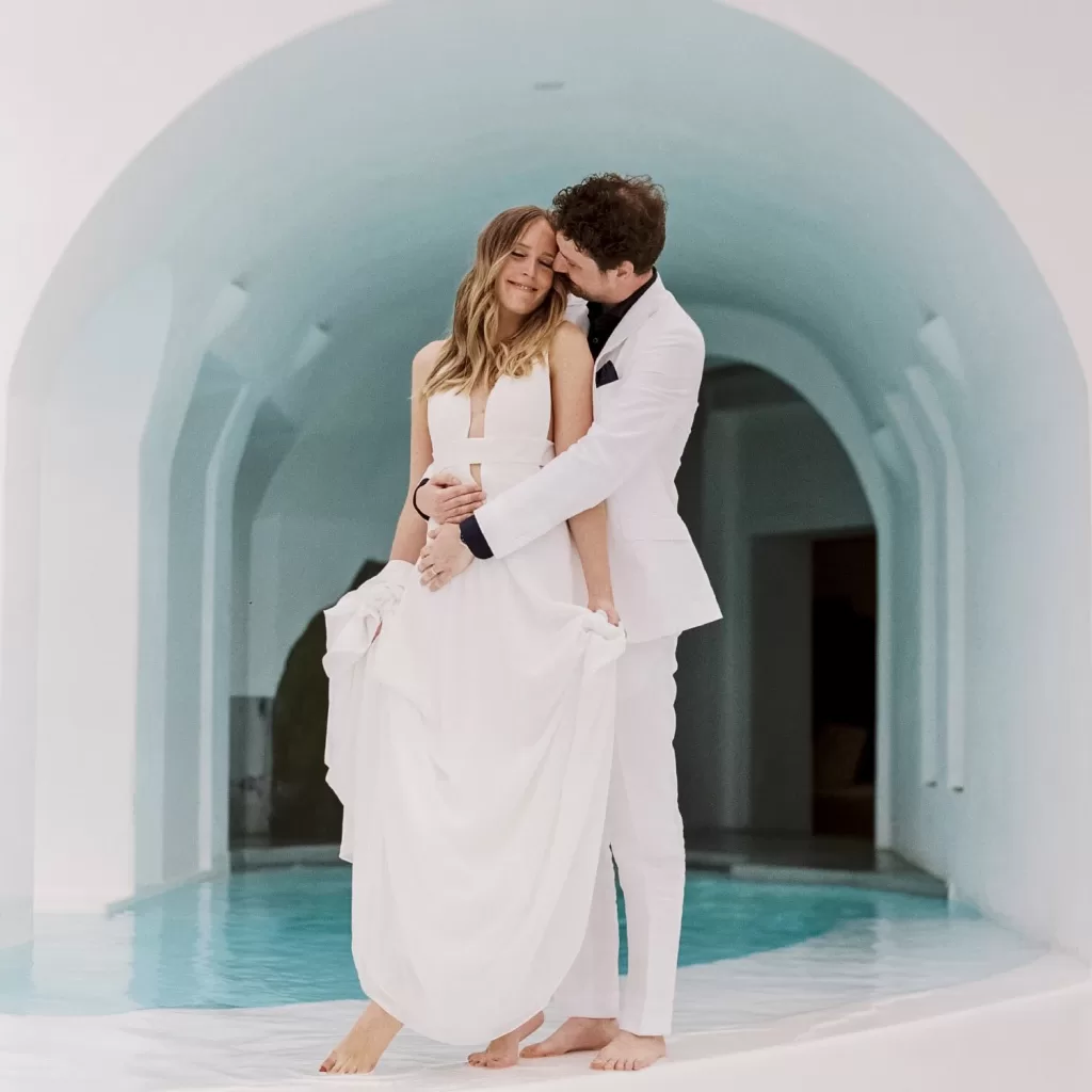 Bride and groom in elegant white attire sharing a quiet moment by the pool at Mykonos Blu.