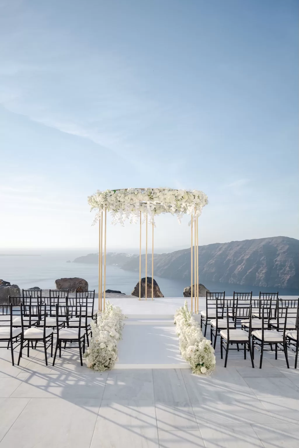 Minimalist white ceremony setup overlooking the sea at Rocabella Santorini