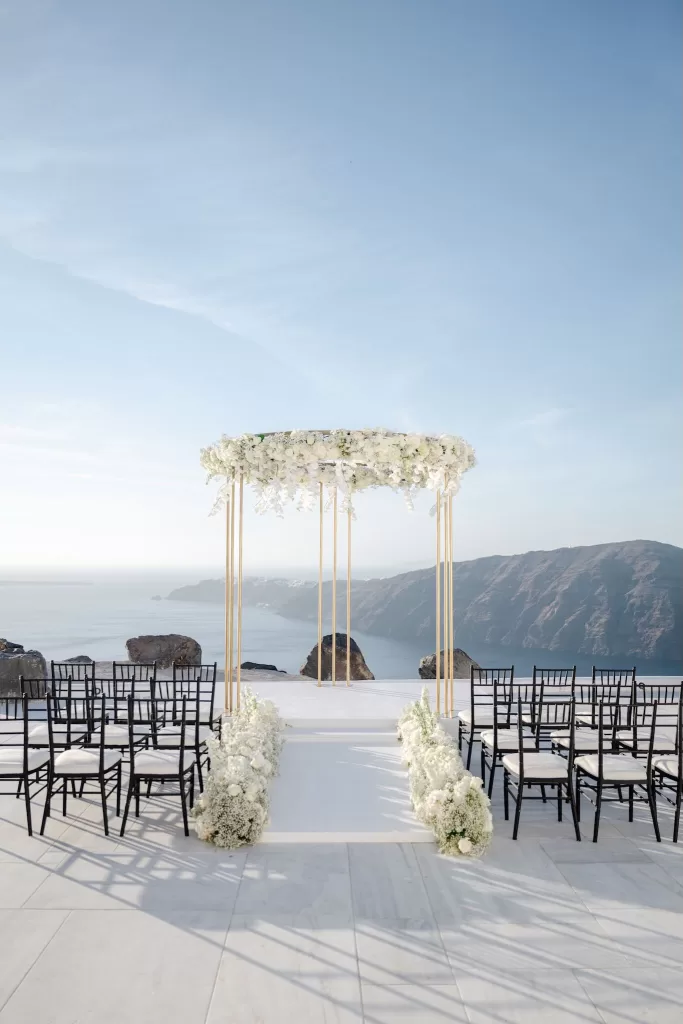 Minimalist white ceremony setup overlooking the sea at Rocabella Santorini