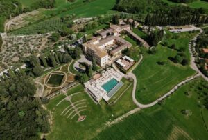 A breathtaking aerial view of Rosewood Castiglion del Bosco, surrounded by rolling Tuscan hills and vineyards.