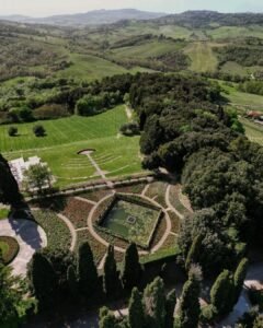 An aerial view of the lush gardens at Rosewood Castiglion del Bosco, framed by cypress trees and elegant pathways.