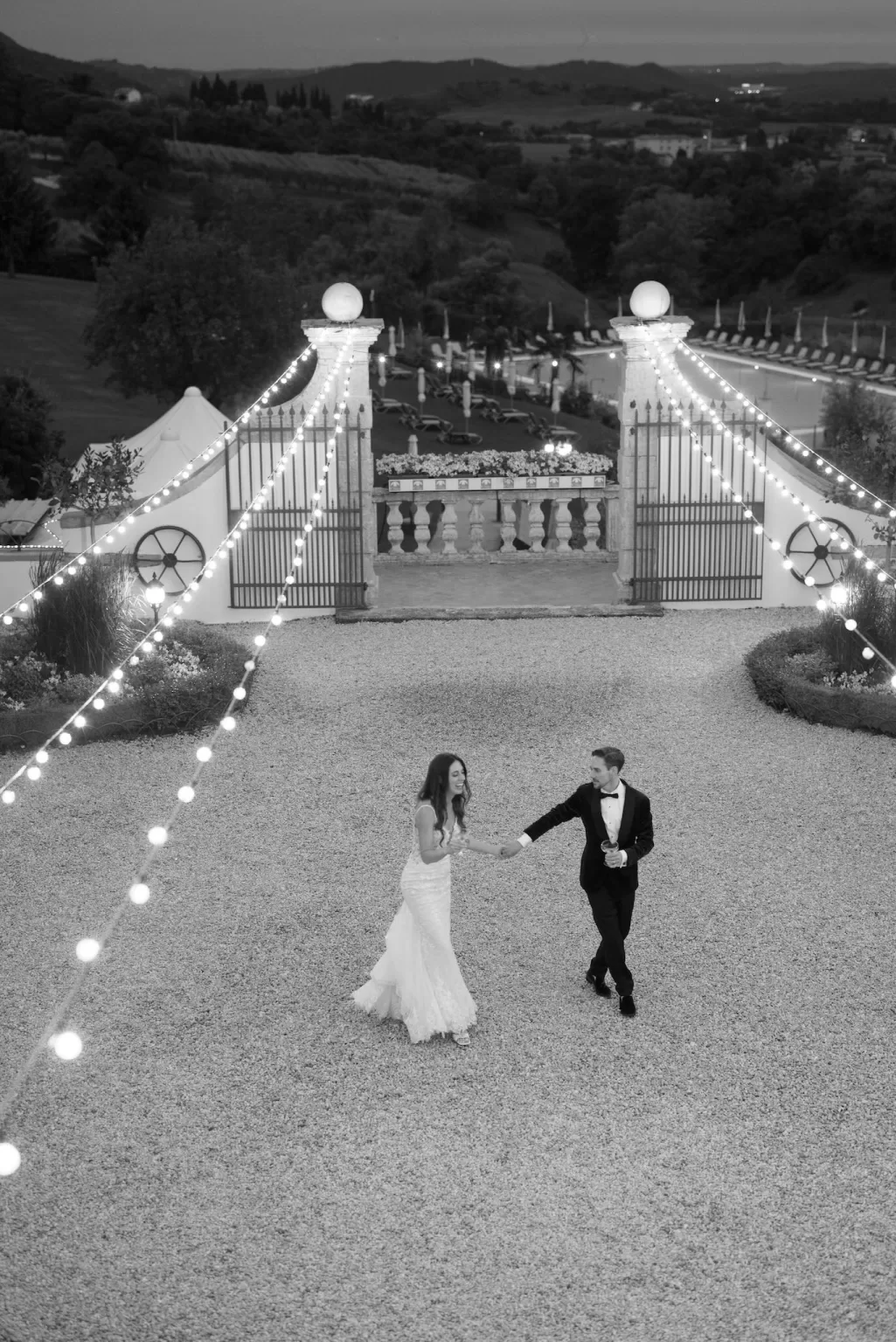 Bride and groom dancing under string lights in the courtyard of Rustico Bertel at night.