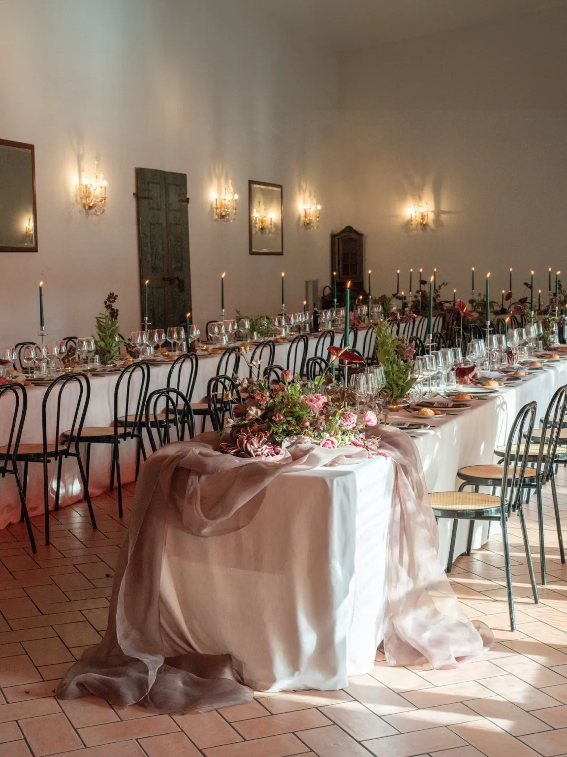 Elegant reception table at Rustico Bertel decorated with candles, flowers, and flowing fabric.