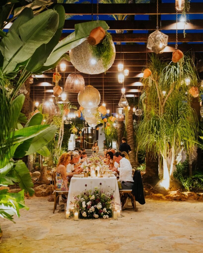 Guests dining under hanging lights at Six Senses Ibiza, surrounded by tropical foliage and warm evening ambiance.