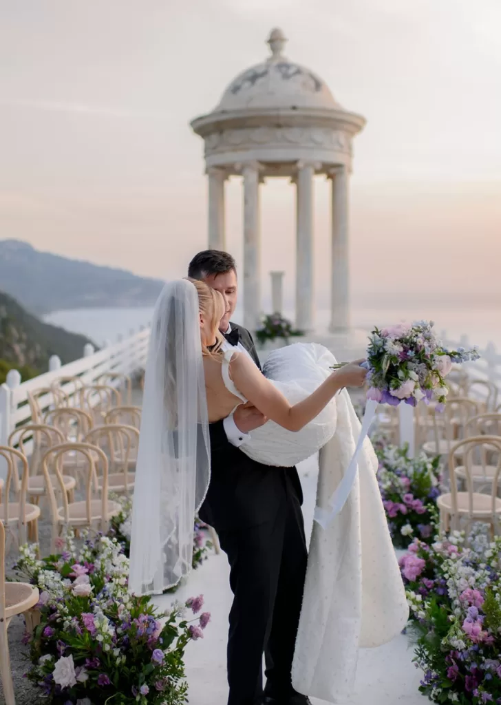 Just married couple kisses joyfully at Son Marroig as guests cheer with fans and parasols.