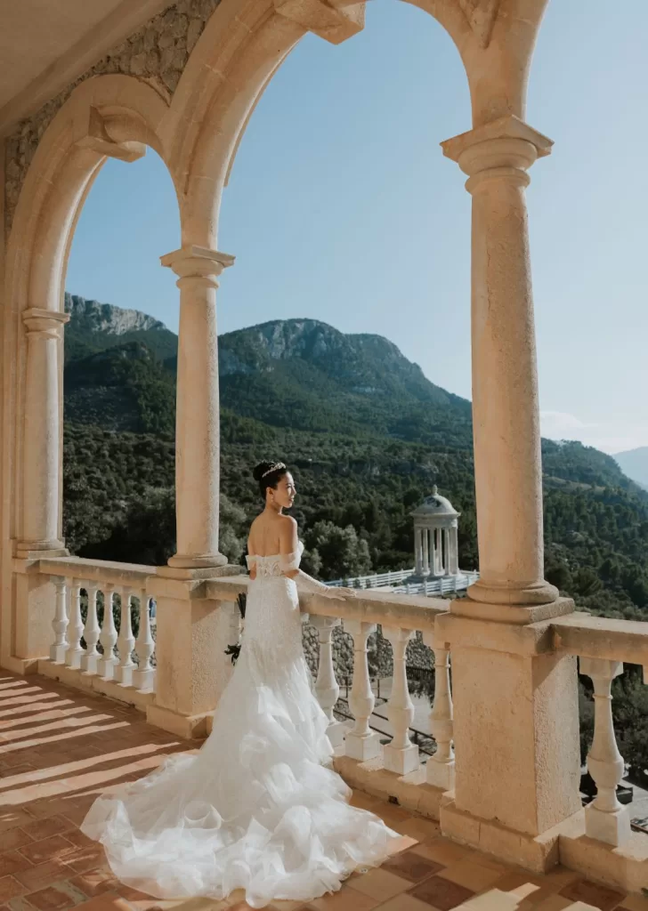 Bride in fitted gown framed by arches and sweeping landscape views on the terrace at Son Marroig.