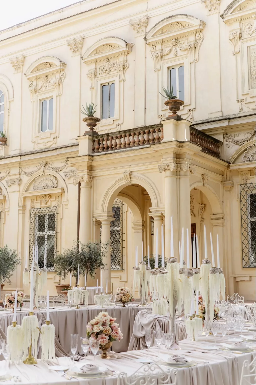 Romantic wedding tablescape with blush flowers and taper candles outside Villa Aurelia