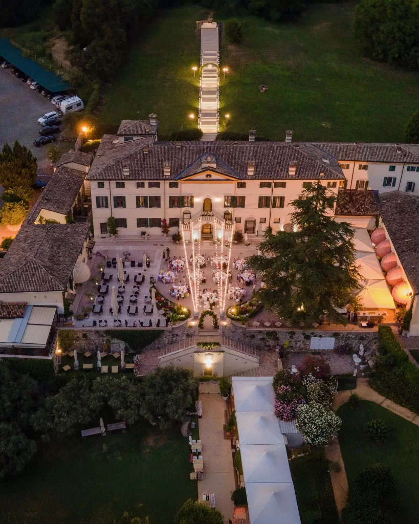 Aerial view of an outdoor reception at Villa Cariola with string lights and round dinner tables
